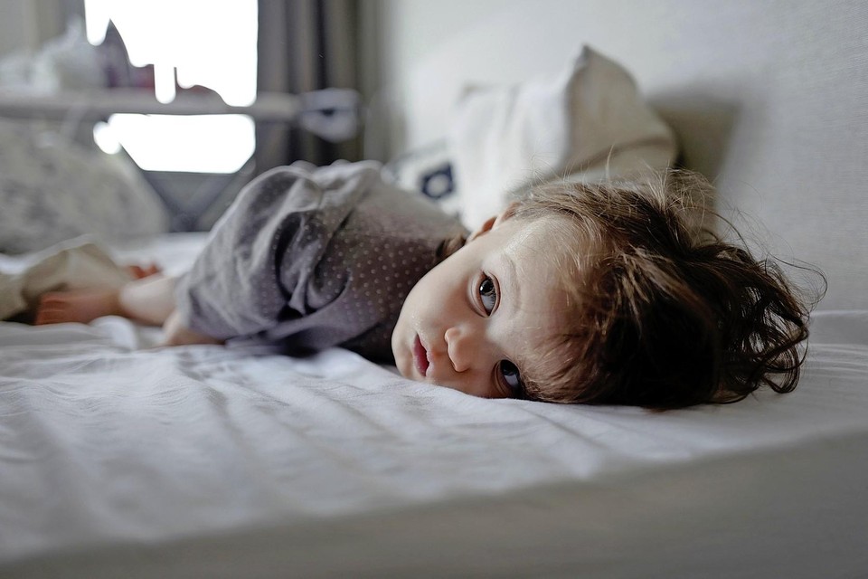 Een kind ligt met griep op bed.