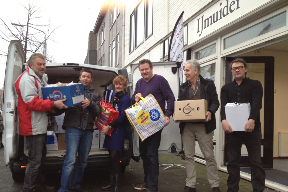 Redacteuren van de IJmuider Courant helpen een handje bij het inladen van de kerstpakketten. Archieffoto