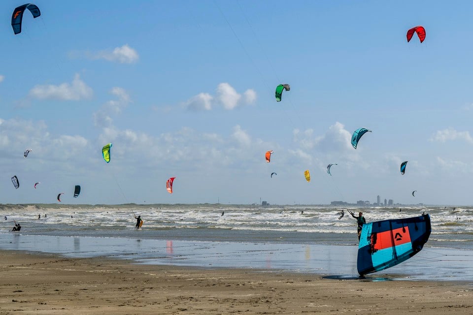 Kitesurfers op het strand van IJmuiden genieten van de harde wind
