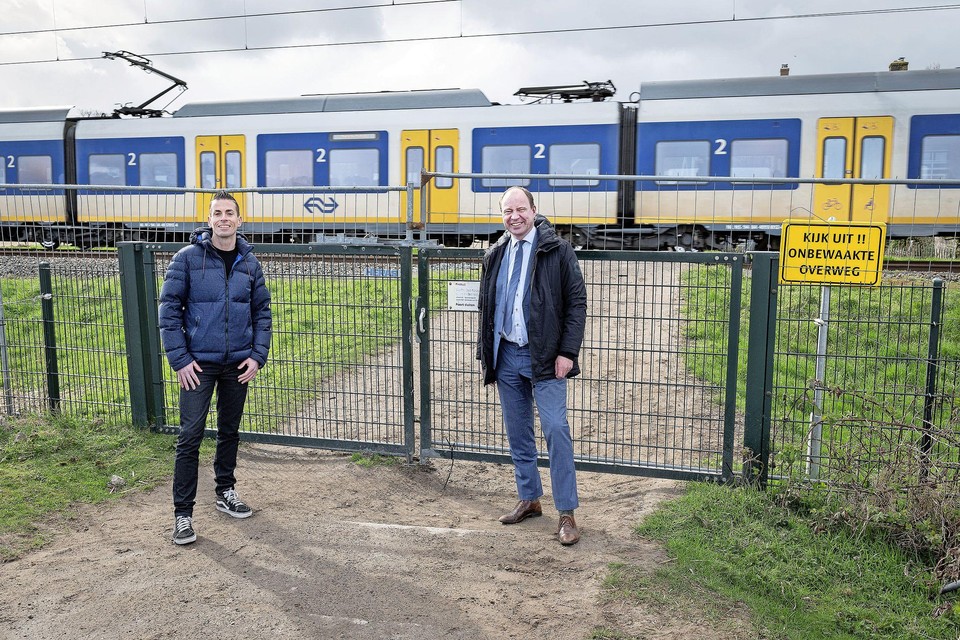 Harro Homan, regiodirecteur Prorail, en de Velsense wethouder Bram Diepstraten (rechts) sluiten de onbewaakte overweg bij boerderij Sinneveld definitief af.