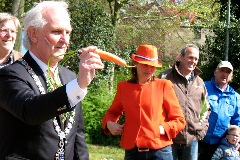 Burgemeester Pieter Broertjes met een oranje stuk groente.