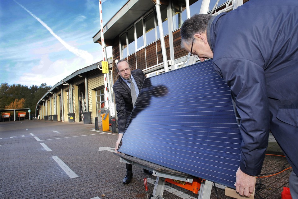 Wethouder Sven Lankreijer (l) en Peter van Drenth, voorzitter van de Energie Coöperatie Eemnes, zetten het eerste zonnepaneel op een liftje naar het dak van de gemeentewerf Eemnes.