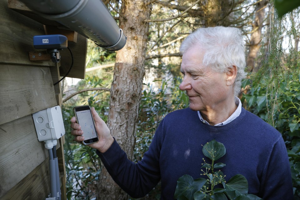 Evert Lammers bekijkt op zijn telefoon wat de fijnstofsensor in zijn achtertuin (links) heeft gemeten.