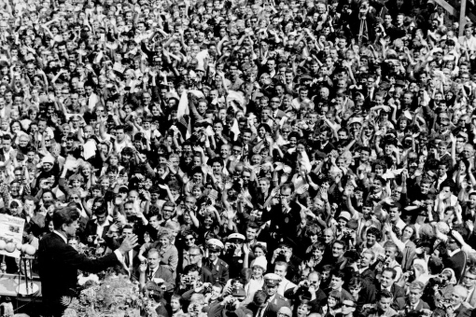 John F Kennedy zwaait naar mensenmassa, die zich bij het Berlijnse raadhuis Schöneberg heeft verzameld. 
