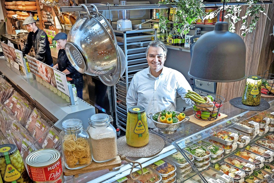 Serdar Tolenaar in zijn Plus-supermarkt  met op de voorgrond in het schap Mama’s Maaltijden. Achter Tolenaar de keuken waarin het allemaal begon.