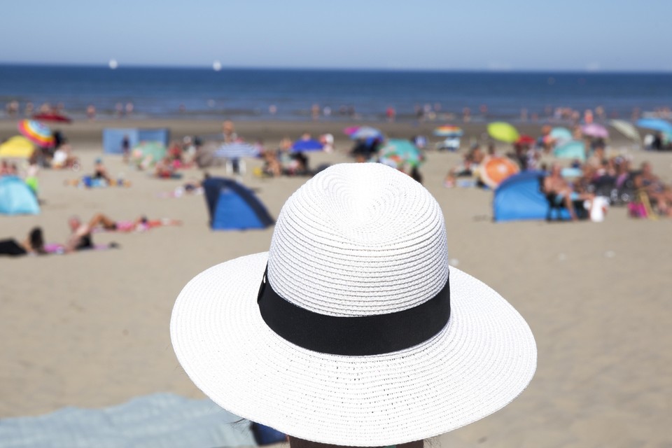 Sonja beziet het vrolijke strandleven vanonder haar hoed.