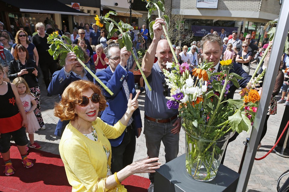Marijke Helwegen, met assistentie van burgemeester en wethouders, vult de bloiemenvaas.