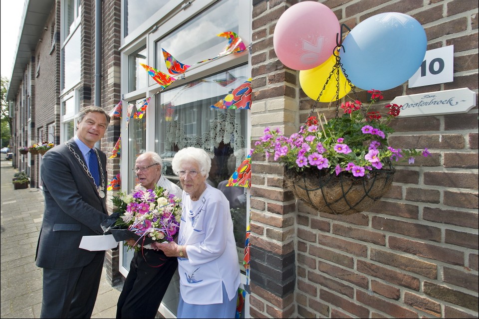 Burgemeester Schneiders reikt een bloemetje uit aan het echtpaar Oosterbroek. Foto United Photos/Paul Vreeker