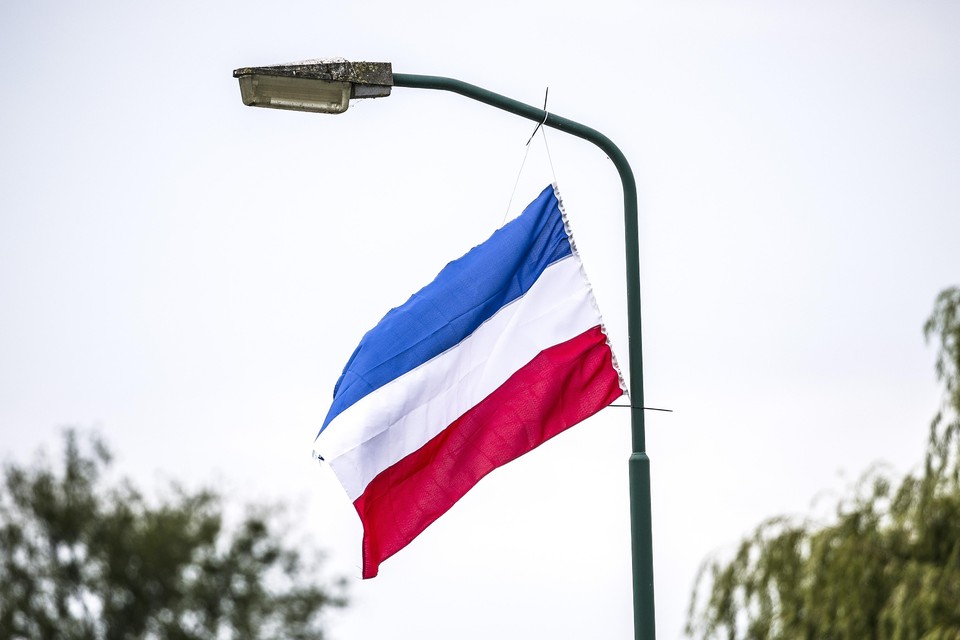 Een omgekeerde Nederlandse vlag aan een lantaarnpaal.
