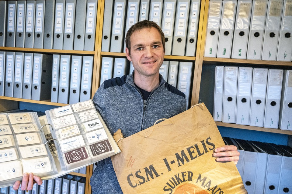 Marcel Bekema voor zijn verzameling suikerzakjes. Rechts in zijn hand de grootste suikerzak uit zijn collectie: eentje van 50 kilogram.