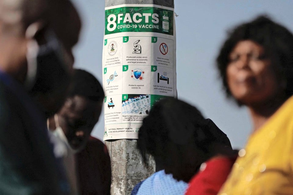 Nigerianen lezen de nieuwe maatregel die door de regering is afgekondigd en die verplichte vaccinatie voor ambtenaren noodzakelijk maakt. Zonder vaccinatie wordt de toegang tot het werk geweigerd.