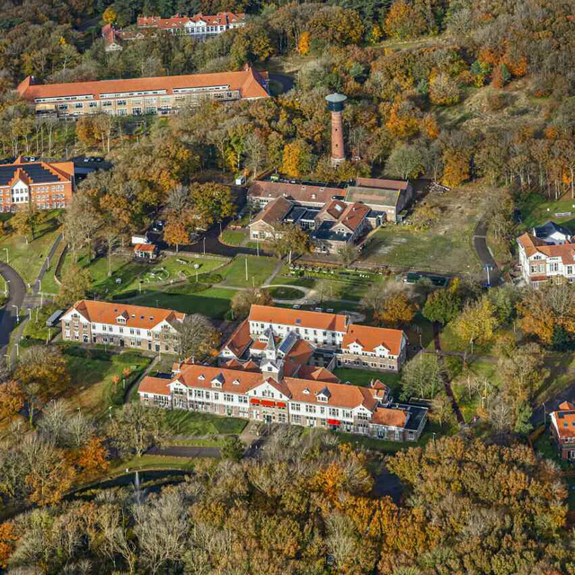 Het hoofdgebouw met de klassieke toren van voormalig psychiatrisch ziekenhuis Duin en Bosch en de watertoren in de herfst.