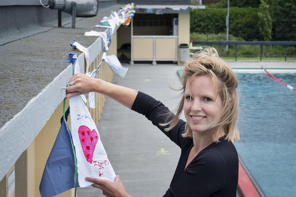 Judith van der Wildt hangt de coronavlaggenlijn op in openluchtzwembad De Houtvaart.