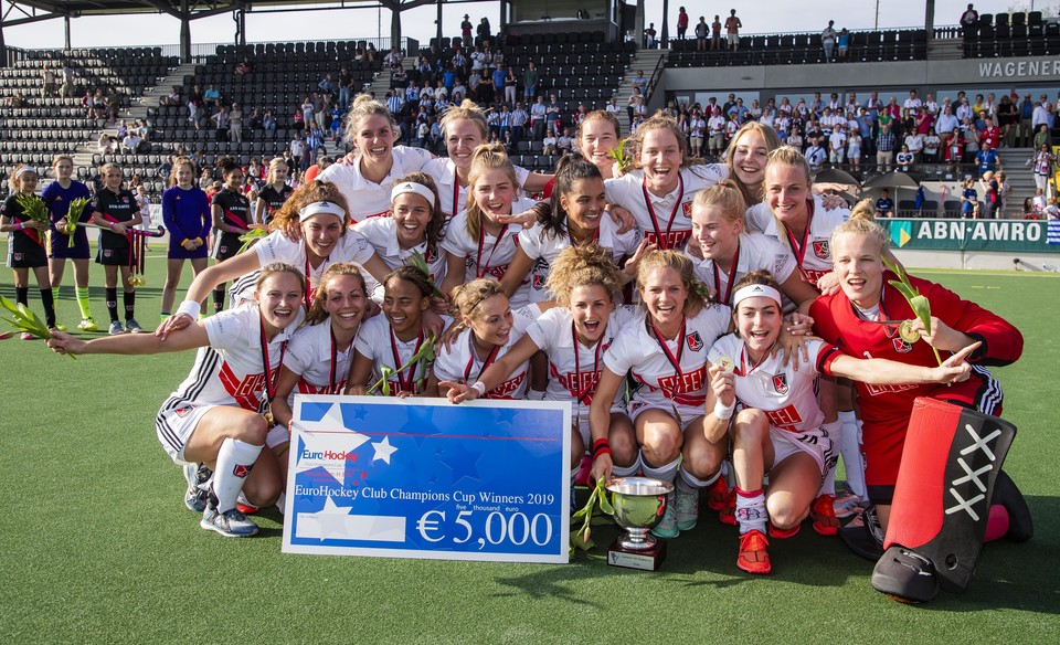 Opgetogen speelsters van Amsterdam, met rechstonder Anne Veenendaal, vieren de winst van de EHCC na de walk-over in de finale tegen het Spaanse Real Sociedad.
