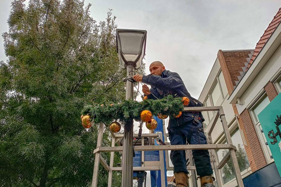Jeff Bouwes hangt de feestversiering op aan de lantaarnpalen in de Beverwijkse binnenstad.