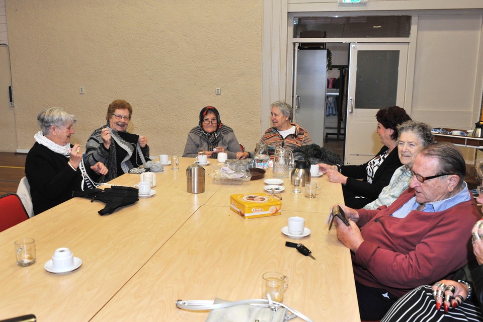 Senioren op de koffie bij Wijk aan Duin. Truus zit rechts aan de kop van de tafel.