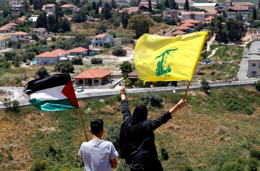 Libanezen zwaaien bij de grens met Israël met de Palestijnse vlag en een vlag van Hezbollah.