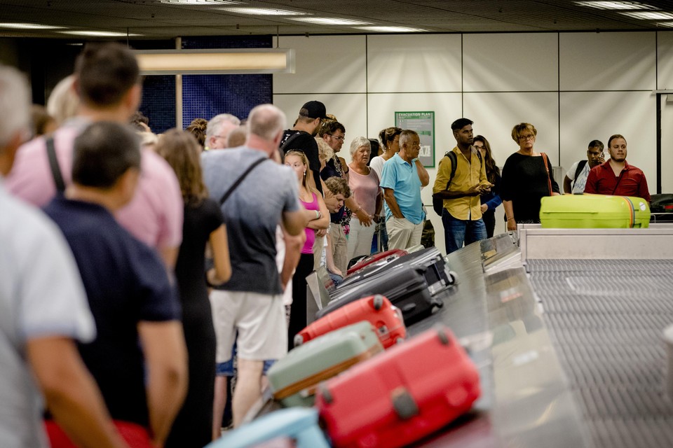Reizigers wachten op hun koffers bij een bagageband op de luchthaven Schiphol. (Archiefbeeld)