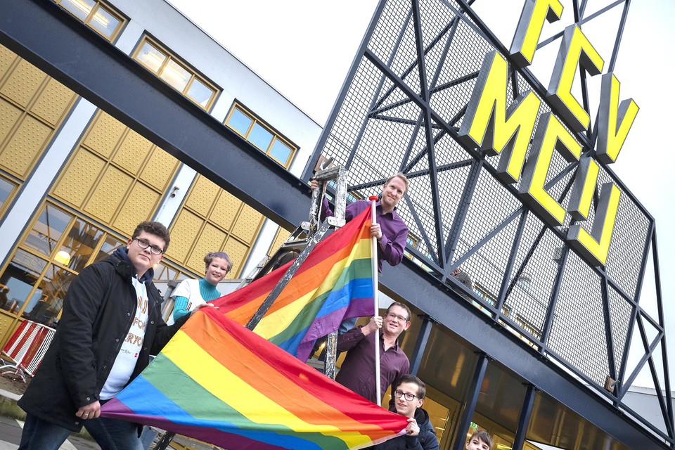 Leerlingen van het Technisch College hangen de regenboogvlag uit met wethouder Dinjens (bovenaan de trap) en Marc Hillebrink van COC Kennemerland.