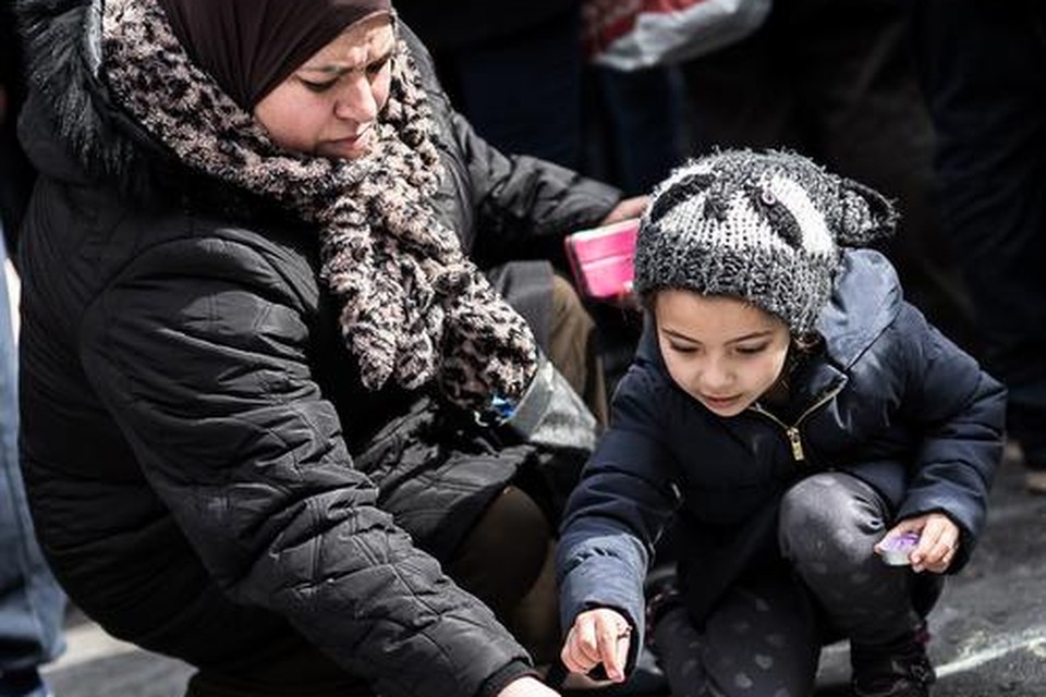 A woman and a small child light a candle at a memorial for victims of attacks in Brussels on Wednesday, March 23, 2016. Belgian authorities were searching Wednesday for a top suspect in the country's deadliest attacks in decades, as the European Union's capital awoke under guard and with limited public transport after scores were killed and injured in bombings on the Brussels airport and a subway station. (AP Photo/Valentin Bianchi) ORG XMIT: VLM158