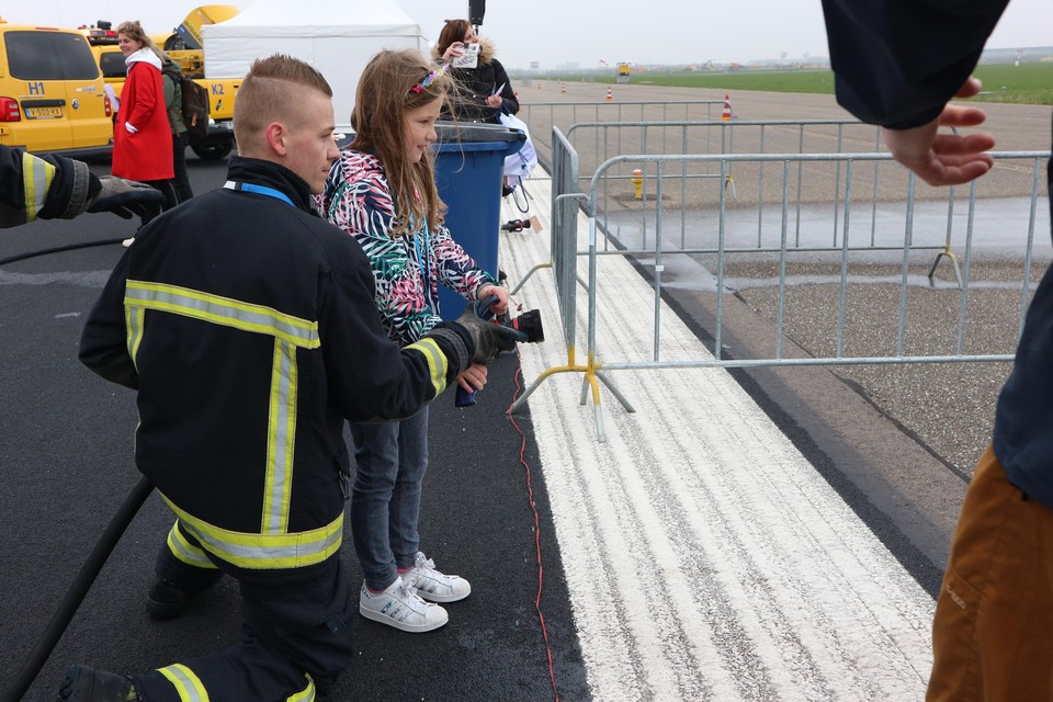 Roos krijgt les van een brandweerman van Schiphol.