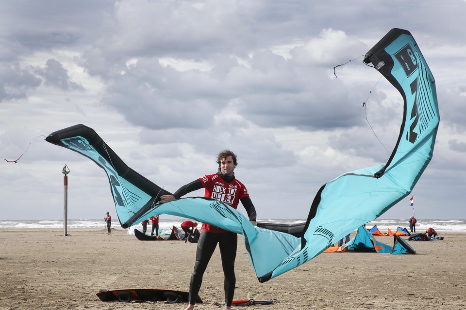 Surfer houdt zijn kite in bedwang op het strand.