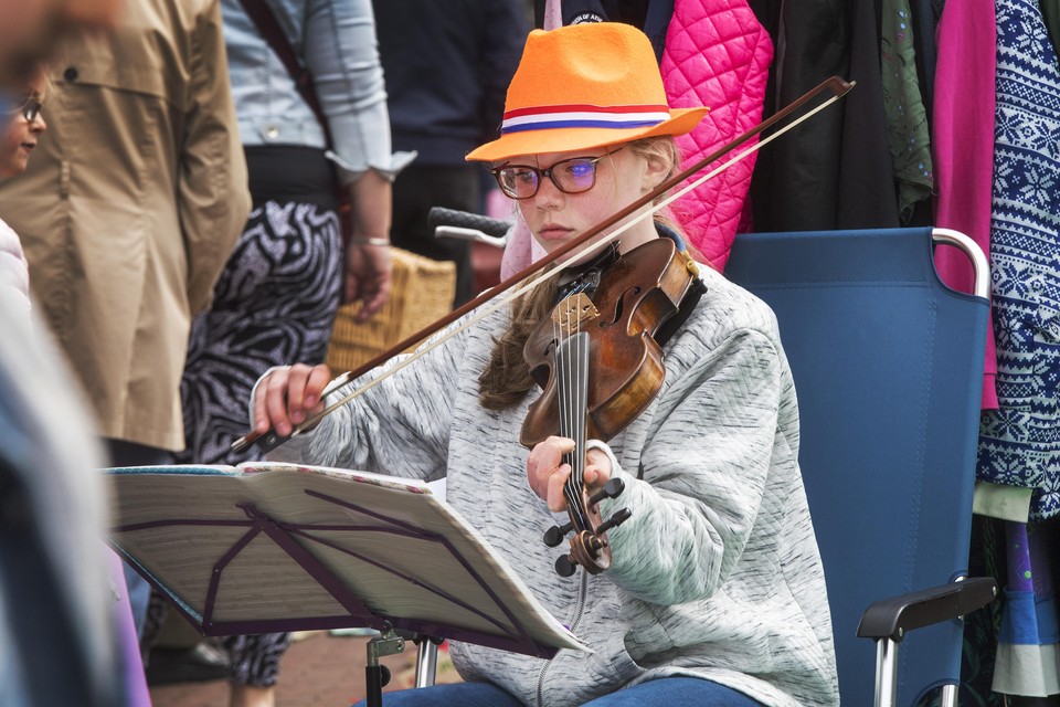 Een meisje speelt viool op de vrijmarkt in de Lange Nieuwstraat.